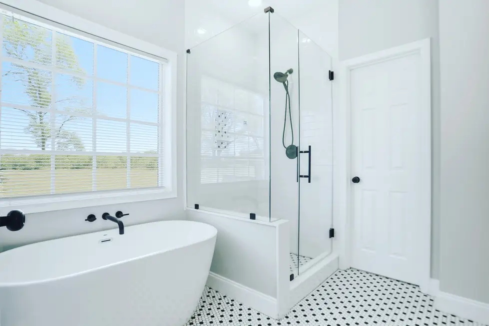 Primary bathroom with a freestanding soaking tub, glass walk-in shower and penny tile floor, photographed for a listing